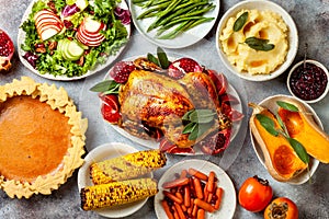 Thanksgiving dinner table with roasted whole chicken or turkey, green beans, mashed potatoes, cranberry sauce, grilled vegetables