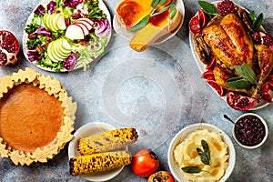 Thanksgiving dinner table with roasted whole chicken or turkey, green beans, mashed potatoes, cranberry sauce, grilled vegetables