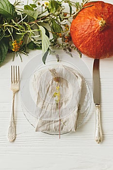 Thanksgiving dinner table setting, eco friendly arrangement. Stylish plate with cutlery and autumn decorations, pumpkin, natural