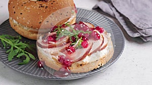 Thanksgiving food concept. Bagel sandwich with turkey and cranberry sauce on gray plate.