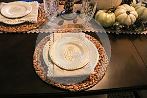 Thanksgiving formal table setting with pumpkin embossed dishes and natural fiber runner and napkins and woven place mats