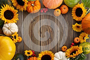 Thanksgiving framework. Flowers, pumpkins and fallen leaves on wooden background. Copy space for text. Halloween