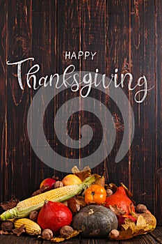 Thanksgiving greetings. Pumpkins, vegetables, nuts, dry leaves on a wooden background, top view. Kaligraphic capital inscription