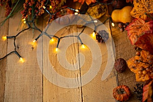 Thanksgiving or Halloween, Autumn composition with dry leaves and small pumpkins on an old wooden table with glowing lights. View