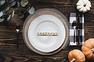Thanksgiving place setting with grateful message over a wood background