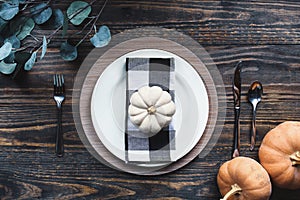 Thanksgiving place setting over a rustic wood background with three pumpkins