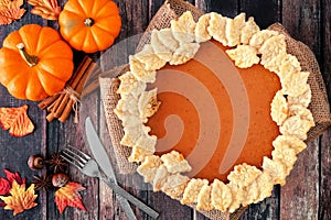 Thanksgiving pumpkin pie with autumn leaf pastry design, overhead scene on rustic wood