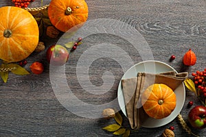 Thanksgiving season still life with ripe pumpkins, plate and autumnal fruits on rustic wooden table. Flat lay, top view, copy