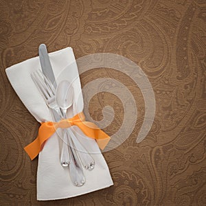 Thanksgiving Table Place Setting with silverware, Cloth Napkin on Brown Damask Textured Tablecloth with room or space for copy, te