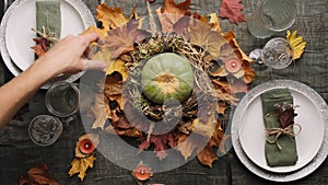 Thanksgiving table set. Woman decorates dinner table with autumnal arrangement.