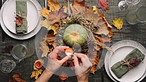 Thanksgiving table set. Woman lights candles to decorate autumnal Thanksgiving dinner table.