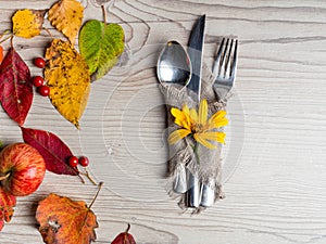 Thanksgiving table setting cutlery on the autumn background with autumn leaves,yellow flower on wooden surface