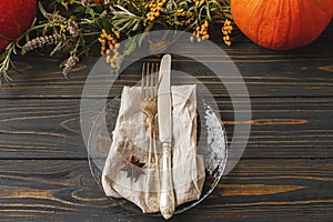 Thanksgiving table setting. Cutlery, linen napkin, anise, autumn decor and pumpkin on rustic wood