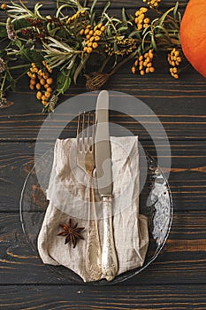 Thanksgiving table setting. Cutlery, linen napkin, anise, autumn decor and pumpkin on rustic wood