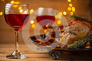 The Thanksgiving traditional turkey on the plate isolated on wooden background. The glasses with red wine are on the table. Yellow