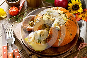 Thanksgiving Turkey dinner. Baked pumpkin stuffed with Turkey, rice and vegetables on rustic background.