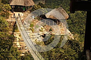 THATCH COVERED SHELTERS AT THE END OF SUSPENSION BRIDGE OVER ORIBI GORGE