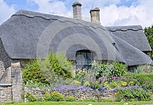 Thatched roof house with garden in bloom in idyllic english village .