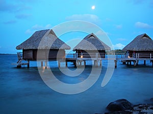 Thatched roof overwater bungalows at blue hour photo