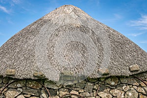 The thatched roof of a round house. metal cart wheel rims