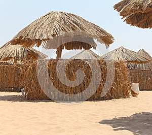 Thatched sunshades and furniture for tourists, on a yellow sand beach. Egyptian hotel beach.