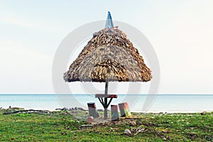 Thatched umbrella shading a picnic table on a sandy beach photo