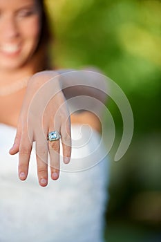 Thats quite the rock. Cropped closeup shot of a young bride showing off her wedding ring to the camera.