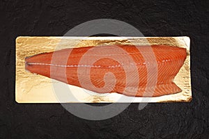 Thawed salmon or sockeye salmon fillet on a dark textured stone background