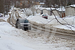 Thawed snow on the road up the mountain in the town in winter, The car is driving on a slippery road