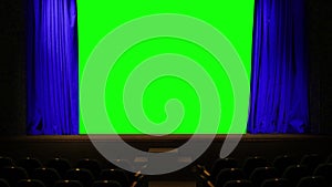 The theater curtain of blue color in the hall on the stage moves to both sides behind it is a green background