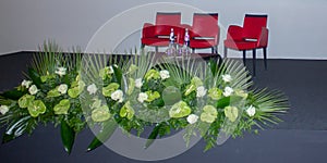 Theater stage photo with three red chairs and beautiful roses.