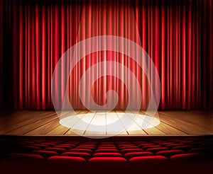 A theater stage with a red curtain, seats and a spotlight.