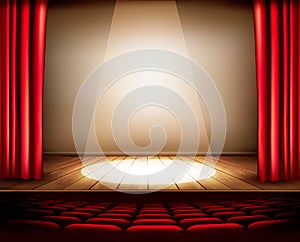 A theater stage with a red curtain, seats and a spotlight.