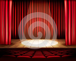 A theater stage with a red curtain, seats and a spotlight