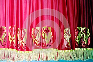 Theatrical red velvet curtain with gold pattern background