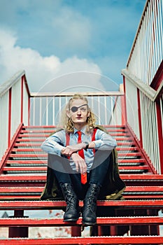 A theatrically dressed pseudo soldier or pirate with a blindfold in one eye sits on the stairs.