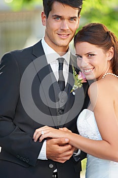 Their love is almost tangible. A young married couple standing together and smiling on their wedding day.