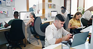 Their office gets busier by the day. a young businessman using a laptop in a modern office.