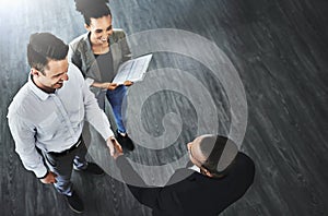 Their team continues to grow. High angle shot of two businesspeople shaking hands in an office.