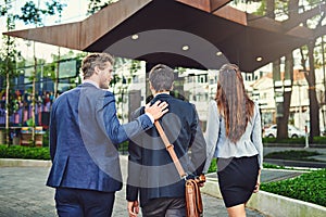 On their way to the seminar. Rearview shot of unrecognizable businesspeople walking to a building together outside.