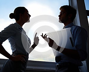 On their way to the top. Silhouette of two young businesspeople standing in front of a window.