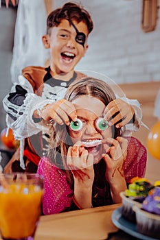 Brother and children feeling funny while eating thematic sweets for Halloween