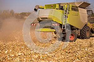 The theme is agriculture. A modern combine harvester in the field performs grain harvesting on a sunny day against a blue sky.