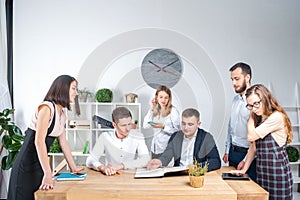 Theme is business and teamwork. A group of young Caucasian people office workers holding a meeting, briefing, working with papers