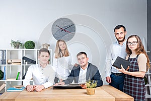 Theme is business and teamwork. A group of young Caucasian people office workers holding a meeting, briefing, working with papers