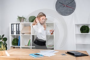 Theme business woman at work. Beautiful young caucasian woman business man working standing in the office near the table, checks