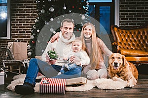 Theme Christmas and New Year family circle and domestic pet. Mom dad and child 1 year old Caucasian woman sitting on