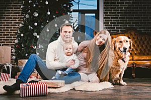 Theme Christmas and New Year family circle and domestic pet. Mom dad and child 1 year old Caucasian woman sitting on floor near Ch