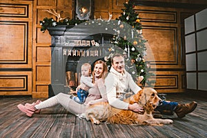 Theme Christmas and New Year family circle. Young Caucasian family with 1 year old child dog breed Labrador Golden Retriever