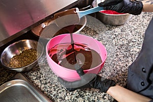 Theme cooking chocolate. Close-up of a hand. Young Caucasian woman cook with tattoo and in uniform prepares to make hot thick